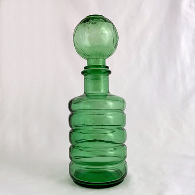 A fabulous green art glass round ribbed genie bottle with a round diamond patterned stopper. This superb mid-century piece of art glass would make a unique addition to your home decor collection. Perfect as a decanter, vase or decor piece. These bottles are incredibly beautiful and highly collectible. Produced by glass artisans in the Empoli region of Italy, circa 1950s to 1970s.  In excellent vintage condition, no chips or cracks.   Measures 3 3/4 x 11 inches
