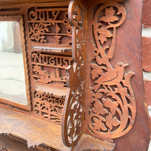 Load image into Gallery viewer, Incredible primitive antique Father Time handmade wood scroll saw wall hung shelf depicting the months of the year with scenes of figures, flora and fauna including birds, rabbits and flowers depicting an activity appropriate to the month, topped with a lounging Father Time with sycthe and hourglass. There are a total of 10 shelves which are notched together and removable, in addition there are 4 mirrors.  In as found condition with a corder of the backboard damaged.
