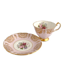Load image into Gallery viewer, Stunning vintage teacup and saucer decorated with a pale pink exterior with a gold gilt pattern of a shells and leaves along with a white interior with a sweet field berry motif on the inside of the teacup and middle of the saucer. Produced by The Paragon China Company, England, circa 1950. In excellent condition, free from chips/cracks/repairs. Marked on the bottom with single warrant stamp.

