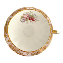 Load image into Gallery viewer, Stunning vintage teacup and saucer decorated with a pale pink exterior with a gold gilt pattern of a shells and leaves along with a white interior with a sweet field berry motif on the inside of the teacup and middle of the saucer. Produced by The Paragon China Company, England, circa 1950. In excellent condition, free from chips/cracks/repairs. Marked on the bottom with single warrant stamp.
