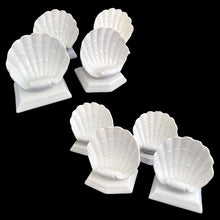 Load image into Gallery viewer, Elevated front angled view of eight white glazed ceramic Fitz &amp; Floyd Oceana clam shell place card holders arranged in two diagonal clusters of four
