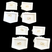 Load image into Gallery viewer, Base view of all eight Fitz &amp; Floyd Oceana ceramic clam shell place card holders showing the original "FF Japan" maker's mark labels on the white glazed bases
