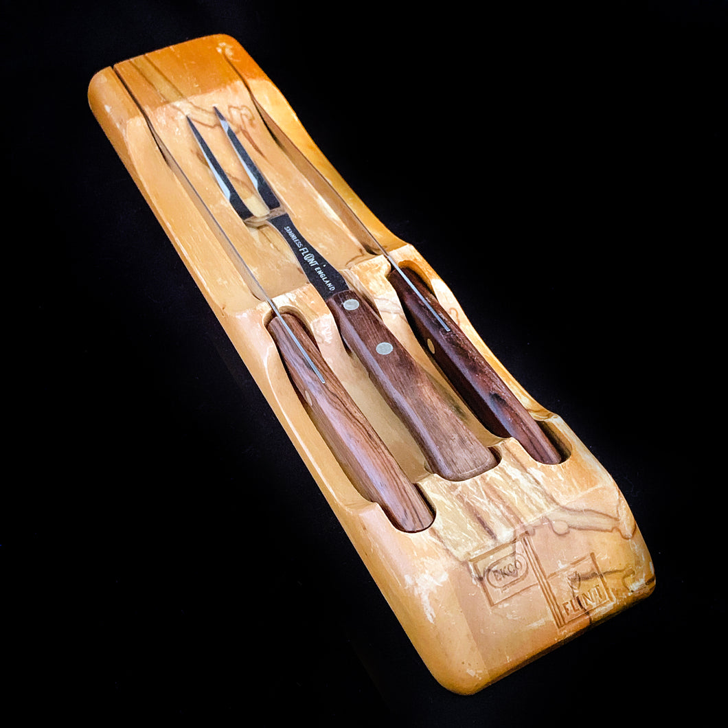 This vintage Flint hollow ground stainless steel three piece cutlery carving knife set is the perfect addition to any kitchen. Crafted by Ekco in England. The cutlery fits nicely into a beautiful hardwood block created by Overton Originals for Ecko. This gorgeous set from the 1950s, remains unused and in excellent condition. Make carving time a pleasure with this stunning vintage set!  The box shows significant wear.   