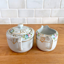 Load image into Gallery viewer, Side detail of vintage Nippon porcelain creamer showing hand-painted floral spray with pink roses, blue flowers, and gold trim
