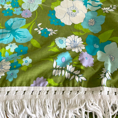 Fabulous vintage summer weight flower power cotton bedspread, finished with a white fringe at the edge. Beautifully crafted, this bedspread features a moss green ground with white, purple, blue and green florals will add colourful flair to your bedroom decor!