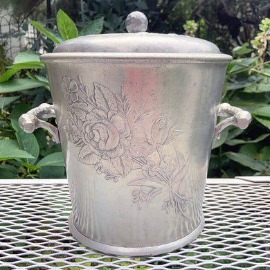 Mid-century vintage hand Forged Roses hammered aluminum ice bucket, two stylized handles, an embossed spray of roses and decorative knob. Hand crafted by the Everlast Metal Products Corporation, USA, circa 1950s. Includes decorative slotted ice spoon. In used vintage condition, in good working order. Lid fits snuggly and the handles are sturdy. The interior liner has surface pitting. Measures 8 x 8 x 9 1/2 inches