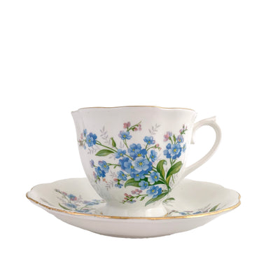Vintage Avon shaped Forget-Me-Not bone china teacup and saucer, features a scalloped edge with hand painted blue flowers and gold gilt rim. Royal Albert, England, 1950s.  In excellent condition, free from chips, cracks and repairs. Makers marks present.  Teacup measures 3 1/4 x 2 3/4 inches | Saucer measures 5 1/2 inches
