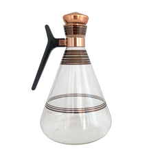 Load image into Gallery viewer, Vintage MCM glass coffee carafe features copper stripes, a black atomic-age bakelite handle, copper cork stopper and metal beauty bowl warmer stand. Crafted by Inland Glass, USA, 1950s. A fabulous mid-century serving piece for yourself or to give as a gift!

In excellent condition. New in box with tags, instructions and 2 candles.

Measures 6 x 9 1/2 inches, spout 2 1/8 inches
