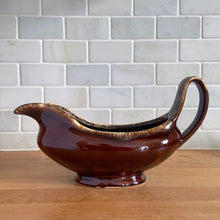 Load image into Gallery viewer, Vintage glossy brown drip glazed ceramic handled gravy boat. Crafted by Hull Pottery, USA, 1960s. A beautiful piece to add to your art pottery tableware collection!

In excellent condition, no chips/cracks/repairs. Maker&#39;s marks.

Measures 10 3/8 x 4 1/4 x 5 5/8 inches
