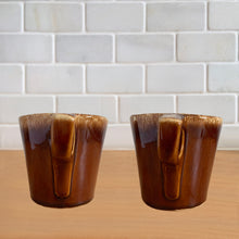 Load image into Gallery viewer, Pair of vintage glossy brown drip glaze mugs. Crafted by Hull Pottery, USA, 1960s. Enjoy any hot beverage in this fabulous retro oven-proof tableware!

In excellent condition, no chips/cracks/repairs. Maker&#39;s marks.

Measures 3 3/4x 3 1/2 inches

Capacity 8 ounces
