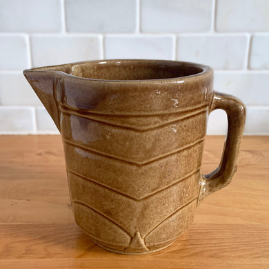 Vintage gloss brown stoneware pitcher with stacked chevron detail. Crafted by Monmouth Western Stoneware, USA, 1920s. Add this utilitarian piece to your farmhouse decor or art pottery collection!

In good vintage condition, tiny flea bite at rim, no cracks/repairs, age-related crazing. Unmarked.

Measures 4 1/2 x 5 inches
