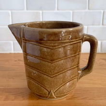 Load image into Gallery viewer, Vintage gloss brown stoneware pitcher with stacked chevron detail. Crafted by Monmouth Western Stoneware, USA, 1920s. Add this utilitarian piece to your farmhouse decor or art pottery collection!

In excellent vintage condition, no chips/cracks/repairs, age-related crazing. Unmarked.

Measures 4 1/2 x 5 inches
