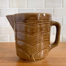Load image into Gallery viewer, Vintage gloss brown stoneware pitcher with stacked chevron detail. Crafted by Monmouth Western Stoneware, USA, 1920s. Add this utilitarian piece to your farmhouse decor or art pottery collection!

In excellent vintage condition, no chips/cracks/repairs, age-related crazing. Unmarked.

Measures 4 1/2 x 5 inches
