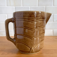 Load image into Gallery viewer, Vintage gloss brown stoneware pitcher with stacked chevron detail. Crafted by Monmouth Western Stoneware, USA, 1920s. Add this utilitarian piece to your farmhouse decor or art pottery collection!

In excellent vintage condition, no chips/cracks/repairs, age-related crazing. Unmarked.

Measures 4 1/2 x 5 inches
