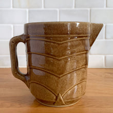 Load image into Gallery viewer, Vintage gloss brown stoneware pitcher with stacked chevron detail. Crafted by Monmouth Western Stoneware, USA, 1920s. Add this utilitarian piece to your farmhouse decor or art pottery collection!

In excellent vintage condition, no chips/cracks/repairs, age-related crazing. Unmarked.

Measures 4 1/2 x 5 inches
