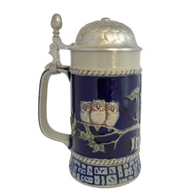 Load image into Gallery viewer, Side view of the full stein with pewter lid closed, cobalt blue body, three baby owls on branches relief, rope border, and geometric base band
