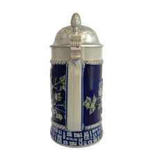 Load image into Gallery viewer, Handle view of the full stein with pewter lid closed, cobalt blue body, branches relief, rope border, and geometric base band, pewter lid with acorn finial
