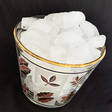 Load image into Gallery viewer, This vintage mid-century Golden Foliage flared glass ice bucket is decorated with a variety of gold leaves against alternating frosted and clear panels with gold rims. Crafted by Libbey Glass, USA, 1953 - 1978. This piece holds a good amount of ice cubes to keep your cocktails cold. Your bar cart has never looked better!

In great vintage condition, no chips, minor wear to the gold rim, but otherwise bright and shiny!

Measures 5 5/8 x 4 3/4 inches
