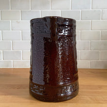 Load image into Gallery viewer, Antique brown glazed stoneware tankard or pitcher, decorated with good luck swastikas. In Native American cultures, the swastika, or Whirling Log as it&#39;s known in Navajo, was a symbol of good fortune, the vehicle of the Culture Hero, or the four winds. This design pre-dates the Nazi era. Crafted by McCoy Pottery, 1920s.

In as found vintage condition, no chips/cracks/repairs. The interior has glaze loss on the bottom and hard water marks.

Measures 7 3/4 x 5 3/4 x 8 1/4 inches (incl. spout/handle)
