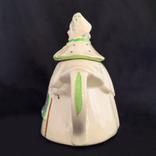 Load image into Gallery viewer, Vintage cream coloured figural &quot;Granny Ann&quot; ceramic teapot featuring a sweet granny holding a brown cane and dressed in a hat and garden frock in green and purple. Crafted by Shawnee Pottery, USA, circa 1940s. Even the spout is a figural basket!  In excellent condition, free from chips/cracks/repairs. Marked on the bottom, &quot;Patented Granny Ann U.S.A.&quot;   Measures 8 x 5 5/8 x 8 1/2 inches   
