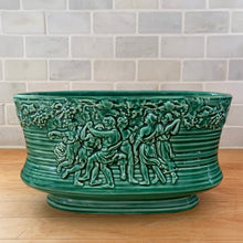 Load image into Gallery viewer, Vintage green glazed Bacchante oval planter jardiniere, shape 115, features embossed toga-clad figures with grapevine detail at the rim. Crafted by Sylvac, England, 1930s 1940s. A nice sized piece for your favourite bulbs and houseplants or use as decor.

In excellent condition, no chips/cracks/repairs.

Measures 9 1/4 x 5 3/4 x 5 1/2 inches
