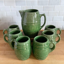 Load image into Gallery viewer, Vintage green barrel ceramic mugs and tankard pitcher set, includes six mugs and and one pitcher. Crafted by McCoy Pottery, USA, 1920s. Off the hop this set gives us all the beer, hot chocolate and cider vibes!

In excellent condition, no chips/cracks/repairs.

Mugs measure 3 3/4 x 4 5/8 inches. Capacity 18oz

Tankard Pitcher measures 5 1/4 x 8 inches. Capacity 72oz
