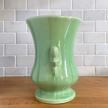 Load image into Gallery viewer, Beautiful vintage Art Deco pale green handled trumpet vase #282 features berry and leaf handles. Crafted by McCoy Pottery, 1946. This vase is must for any art pottery collector. A lovely way to enhance your home&#39;s decor or to give as a gift!

In great vintage condition, chip to underside of foot, no cracks/repairs. Typical manufacturer&#39;s glaze pops/defects. Maker&#39;s mark on the bottom.

Measures 6 x 8 1/8 inches (incl. handle/spout)

