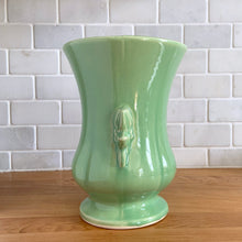 Load image into Gallery viewer, Beautiful vintage Art Deco pale green handled trumpet vase #282 features berry and leaf handles. Crafted by McCoy Pottery, 1946. This vase is must for any art pottery collector. A lovely way to enhance your home&#39;s decor or to give as a gift!

In great vintage condition, chip to underside of foot, no cracks/repairs. Typical manufacturer&#39;s glaze pops/defects. Maker&#39;s mark on the bottom.

Measures 6 x 8 1/8 inches (incl. handle/spout)
