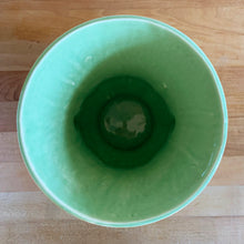 Load image into Gallery viewer, Beautiful vintage Art Deco pale green handled trumpet vase #282 features berry and leaf handles. Crafted by McCoy Pottery, 1946. This vase is must for any art pottery collector. A lovely way to enhance your home&#39;s decor or to give as a gift!

In great vintage condition, chip to underside of foot, no cracks/repairs. Typical manufacturer&#39;s glaze pops/defects. Maker&#39;s mark on the bottom.

Measures 6 x 8 1/8 inches (incl. handle/spout)
