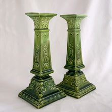 Load image into Gallery viewer, This RARE pair of antique candlesticks from Bretby Pottery are a stunning addition to any home. Crafted in pre-1920 England, they feature a moss green glaze with exquisite raised laurel leaves and rosettes. A must-have for the vintage collector!  In excellent condition. Bretby&#39;s sunburst impressed mark is on the bottom.  Measures 10 inches.
