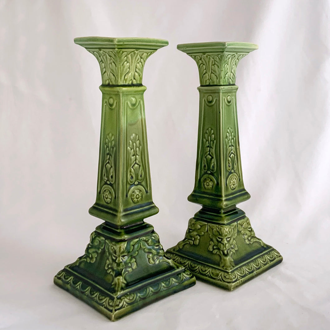 This RARE pair of antique candlesticks from Bretby Pottery are a stunning addition to any home. Crafted in pre-1920 England, they feature a moss green glaze with exquisite raised laurel leaves and rosettes. A must-have for the vintage collector!  In excellent condition. Bretby's sunburst impressed mark is on the bottom.  Measures 10 inches.