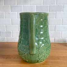 Load image into Gallery viewer, Vintage art deco gloss green ceramic yellow ware pitcher featuring climbing roses on a trellis pattern. Crafted by McCoy Pottery, USA, 1920s. A beautiful piece to add to your art pottery collection!

In excellent condition, no chips/cracks/repairs, age-related crazing. Typical manufacturing glaze pops. Unmarked.

Measures 5 1/4 x 8 3/4 inches
