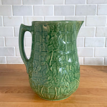 Load image into Gallery viewer, Vintage art deco gloss green ceramic yellow ware pitcher featuring climbing roses on a trellis pattern. Crafted by McCoy Pottery, USA, 1920s. A beautiful piece to add to your art pottery collection!

In excellent condition, no chips/cracks/repairs, age-related crazing. Typical manufacturing glaze pops. Unmarked.

Measures 5 1/4 x 8 3/4 inches
