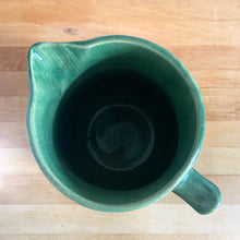 Load image into Gallery viewer, Vintage art deco gloss green ceramic yellow ware pitcher featuring climbing roses on a trellis pattern. Crafted by McCoy Pottery, USA, 1920s. A beautiful piece to add to your art pottery collection!

In excellent condition, no chips/cracks/repairs, age-related crazing. Typical manufacturing glaze pops. Unmarked.

Measures 5 1/4 x 8 3/4 inches
