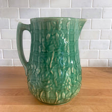 Load image into Gallery viewer, Vintage art deco gloss green ceramic yellow ware pitcher featuring climbing roses on a trellis pattern. Crafted by McCoy Pottery, USA, 1920s. A beautiful piece to add to your art pottery collection!

In excellent condition, no chips/cracks/repairs, age-related crazing. Typical manufacturing glaze pops. Unmarked.

Measures 5 1/4 x 8 3/4 inches
