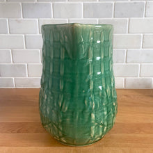 Load image into Gallery viewer, Vintage art deco gloss green ceramic yellow ware pitcher featuring climbing roses on a trellis pattern. Crafted by McCoy Pottery, USA, 1920s. A beautiful piece to add to your art pottery collection!

In excellent condition, no chips/cracks/repairs, age-related crazing. Typical manufacturing glaze pops. Unmarked.

Measures 5 1/4 x 8 3/4 inches
