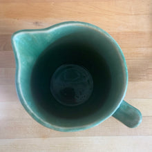 Load image into Gallery viewer, Vintage art deco gloss green ceramic yellow ware pitcher featuring climbing roses on a trellis pattern. Crafted by McCoy Pottery, USA, 1920s. A beautiful piece to add to your art pottery collection!

In excellent condition, no chips/cracks/repairs, age-related crazing. Typical manufacturing glaze pops. Unmarked.

Measures 5 1/4 x 8 3/4 inches
