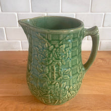 Load image into Gallery viewer, Vintage art deco gloss green ceramic pitcher featuring climbing roses on a trellis pattern. Crafted by McCoy Pottery, USA, 1930s. A beautiful piece to add to your art pottery collection and the perfect complement to any farmhouse, cottagecore, country, or shabby chic home decor!

In excellent condition, minor chip at the foot, no cracks/repairs, age-related crazing. Typical manufacturing glaze pops. Unmarked.

Measures 4 1/4 x 6 3/4 inches
