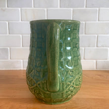 Load image into Gallery viewer, Vintage art deco gloss green ceramic pitcher featuring climbing roses on a trellis pattern. Crafted by McCoy Pottery, USA, 1930s. A beautiful piece to add to your art pottery collection and the perfect complement to any farmhouse, cottagecore, country, or shabby chic home decor!

In excellent condition, minor chip at the foot, no cracks/repairs, age-related crazing. Typical manufacturing glaze pops. Unmarked.

Measures 4 1/4 x 6 3/4 inches
