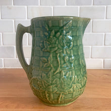 Load image into Gallery viewer, Vintage art deco gloss green ceramic pitcher featuring climbing roses on a trellis pattern. Crafted by McCoy Pottery, USA, 1930s. A beautiful piece to add to your art pottery collection and the perfect complement to any farmhouse, cottagecore, country, or shabby chic home decor!

In excellent condition, minor chip at the foot, no cracks/repairs, age-related crazing. Typical manufacturing glaze pops. Unmarked.

Measures 4 1/4 x 6 3/4 inches
