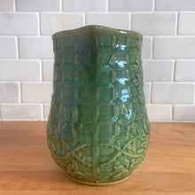 Load image into Gallery viewer, Vintage art deco gloss green ceramic pitcher featuring climbing roses on a trellis pattern. Crafted by McCoy Pottery, USA, 1930s. A beautiful piece to add to your art pottery collection and the perfect complement to any farmhouse, cottagecore, country, or shabby chic home decor!

In excellent condition, minor chip at the foot, no cracks/repairs, age-related crazing. Typical manufacturing glaze pops. Unmarked.

Measures 4 1/4 x 6 3/4 inches
