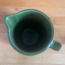Load image into Gallery viewer, Vintage art deco gloss green ceramic pitcher featuring climbing roses on a trellis pattern. Crafted by McCoy Pottery, USA, 1930s. A beautiful piece to add to your art pottery collection and the perfect complement to any farmhouse, cottagecore, country, or shabby chic home decor!

In excellent condition, minor chip at the foot, no cracks/repairs, age-related crazing. Typical manufacturing glaze pops. Unmarked.

Measures 4 1/4 x 6 3/4 inches
