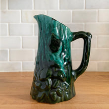 Load image into Gallery viewer, Vintage green drip glaze pitcher, featuring a woodland design of raised mushrooms and knots around a tree trunk. Crafted by Evangeline Pottery, Canada, 1960s. This sweet pitcher makes for a beautiful statement piece or a functional pitcher for your home.

In excellent condition, no chips/cracks/repairs.

Measures 5 x 3 5/8 x 6 1/4 inches
