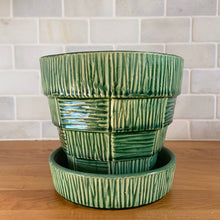 Load image into Gallery viewer, Striking vintage gloss green basketweave planter pot with attached saucer. Crafted by McCoy Pottery, 1953. This rare planter is must for any McCoy art pottery collector!

In as found vintage condition, chipped, two tight hairline cracks, hard water residue. Maker&#39;s mark on the bottom.

Measures 6 1/4 x 5 1/2 inches
