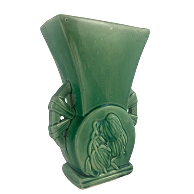 Beautiful vintage gloss green wheel handled vase, features embossed florals. Crafted by McCoy Pottery, 1940s. This vase is must for any art pottery collector!

In excellent vintage condition, minor spot of roughness to the rim along with age-related crazing. Maker's mark on the bottom.

Measures 6 1/2 x 3 3/8 x 9 1/2 inches