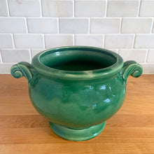Load image into Gallery viewer, Highly collectible vintage mid-century green Art Deco round ceramic art pottery jardiniere planter with curled handles. Crafted by McCoy Pottery, USA, 1950s. The perfect home for your favourite houseplant or succulent!

In excellent vintage condition, no chips/cracks/repairs, age-related crazing. Maker&#39;s mark.

Measures 6 3/4 x 6 inches (10 1/4 inches from handle-to-handle)

