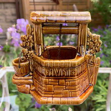 Load image into Gallery viewer, This classic vintage ochre and green ceramic planter features a charming figural wishing well design complete with a bucket and its original brass chain. Inscribed with the phrase &quot;Oh Wishing Well, Grant A Wish To Me,&quot; it adds a whimsical touch to any home decor. Crafted by McCoy Pottery, 1950s. Ideal for collectors of art pottery, this piece combines nostalgic appeal with functional beauty, making it a distinctive gift or a unique addition to your collection.
