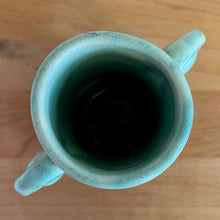 Load image into Gallery viewer, Rare vintage art deco Coronado Art Line pale green vase with double curled handles, 4A. Crafted by Brush McCoy Pottery, 1940s. This unique vase is a must-have for any art pottery collector. A lovely piece to use in your home decor or to give as a gift!

In excellent vintage condition, no chips/cracks/repairs. Marked on the bottom, A4 USA.

Measures 3 1/2 x 4 5/8 inches (incl. handles)
