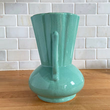 Load image into Gallery viewer, Vintage Art Deco green speckle glazed ceramic flower vase featuring a round base and a ribbed panel design flanked by two handles highlighted with a flower motif. Crafted by York Pottery (precursor to Pfaltzgraff), USA, circa 1930s. A beautiful piece to add to any art pottery collection! Excellent condition. Marked with impressed keystone, York P 288 USA. Measures 5 x 8 inches
