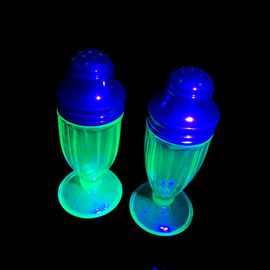 Pair of antique vintage depression era art deco uranium glass Ribbon footed salt and pepper shakers with metal lids. Crafted by Hazel-Atlas Glass, USA, 1930 - 1935. This timeless kitchen accessory and their novel green uranium glass, which glows brilliantly under black light, adds a unique accent to your kitchen and table decor!

In good vintage condition, no chips, one shaker has a horizontal scratch. Age appropriate wear to the lids.

Measures 1 1/2 x 3 3/4 inches